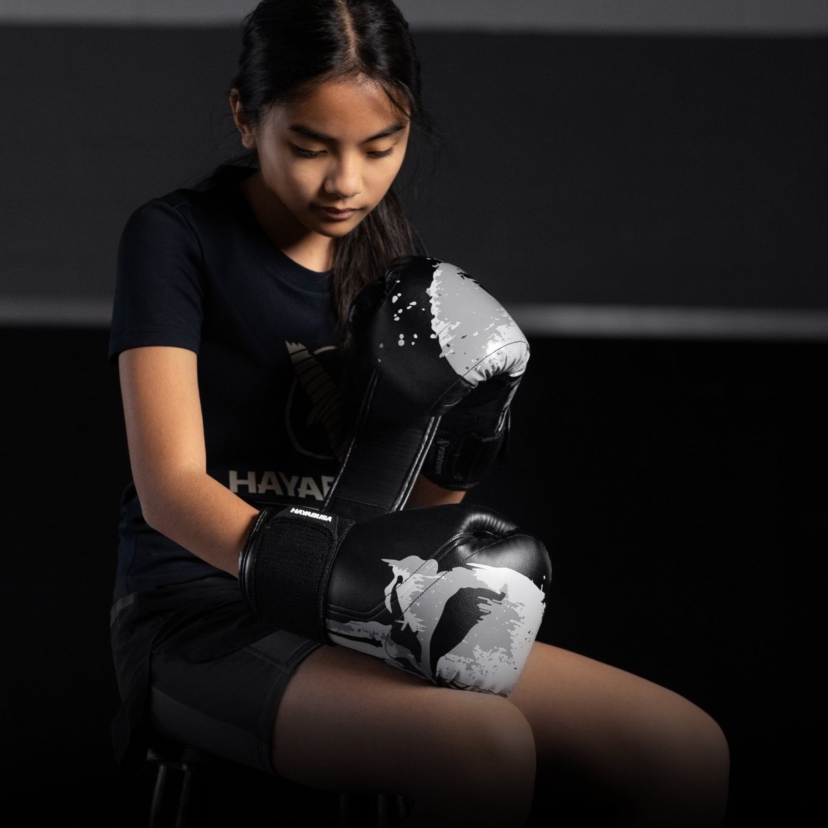 A little girl wearing the black Hayabusa Marvel Punisher boxing gloves in the guard position