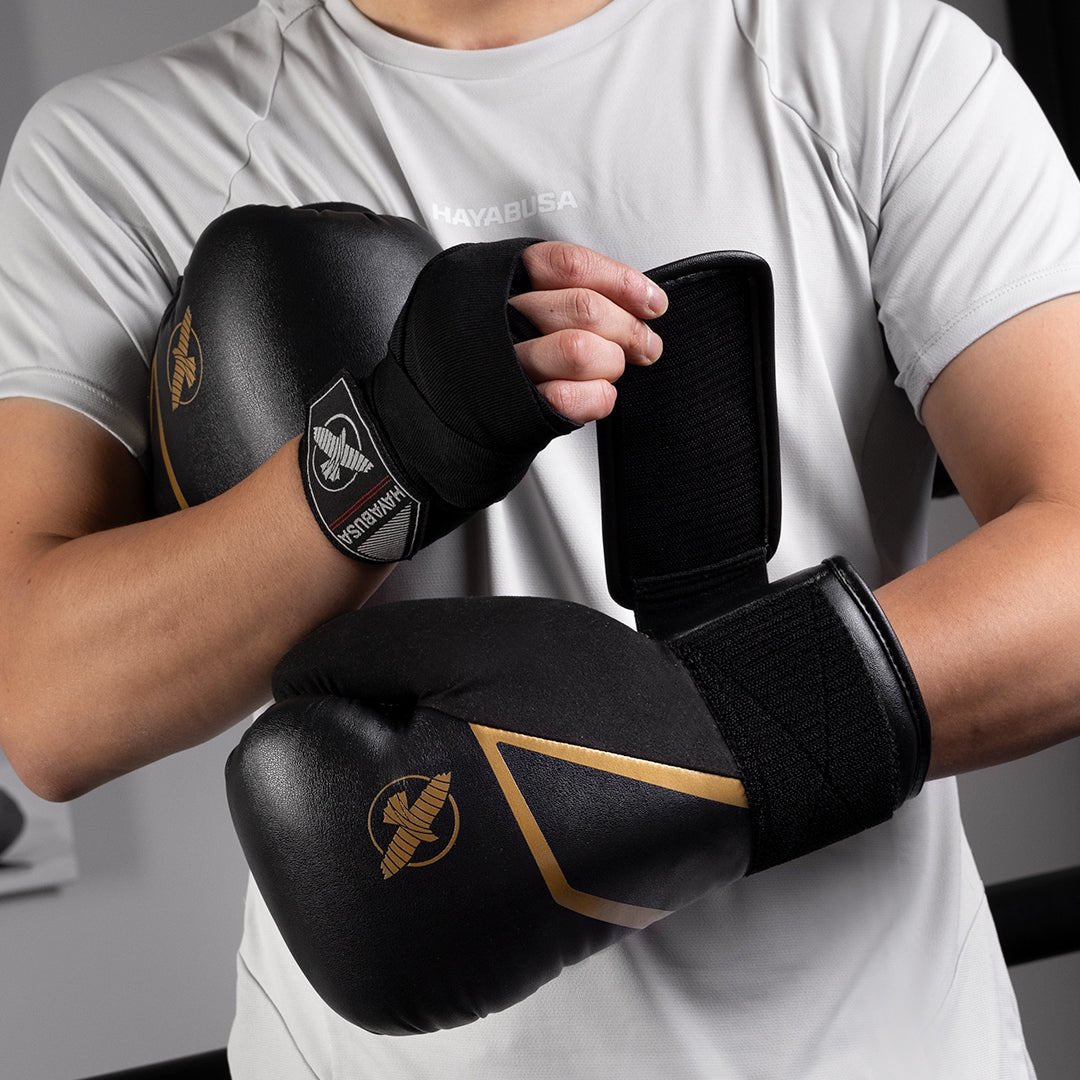 Luvas de boxe Hayabusa E1 pretas e douradas usadas durante um treino com saco de pancadas