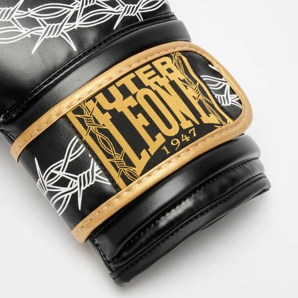 Detalhe macro do patch LEONE x IUTER tecido dourado no fecho de velcro