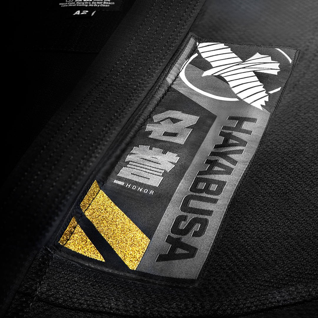 Detail close-up dari tempelan kanji dan trim pada jaket Ascend Gi hitam