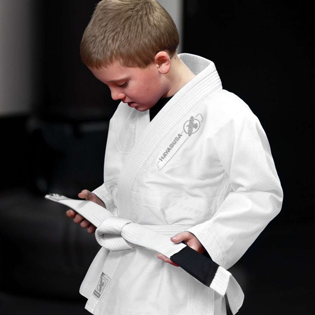 Un niño entrenando en el tatami con el kimono blanco Hayabusa Essential BJJ