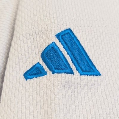 Detalle de las tres rayas de Adidas y el logo azul de la versión italiana en el hombro del judogi