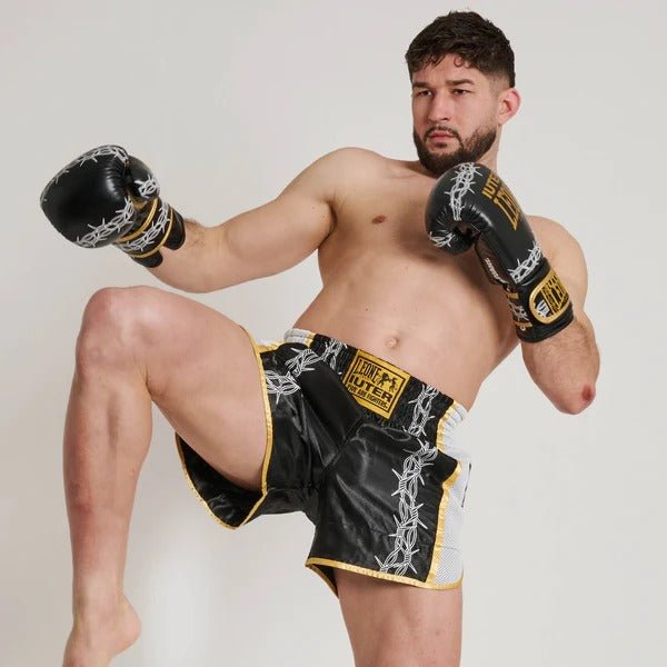 Athlete in Muay Thai kick pose showing flexibility of Barbed Wire shorts