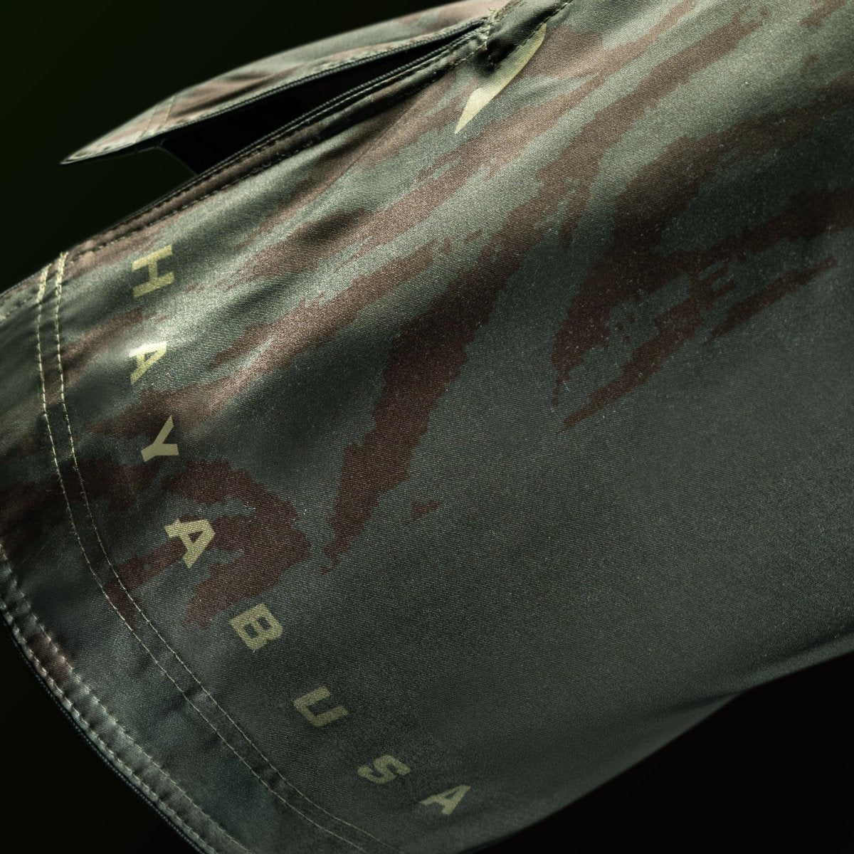 Detalle de los gráficos y la escritura Hayabusa en la pernera del short tres cuartos verde