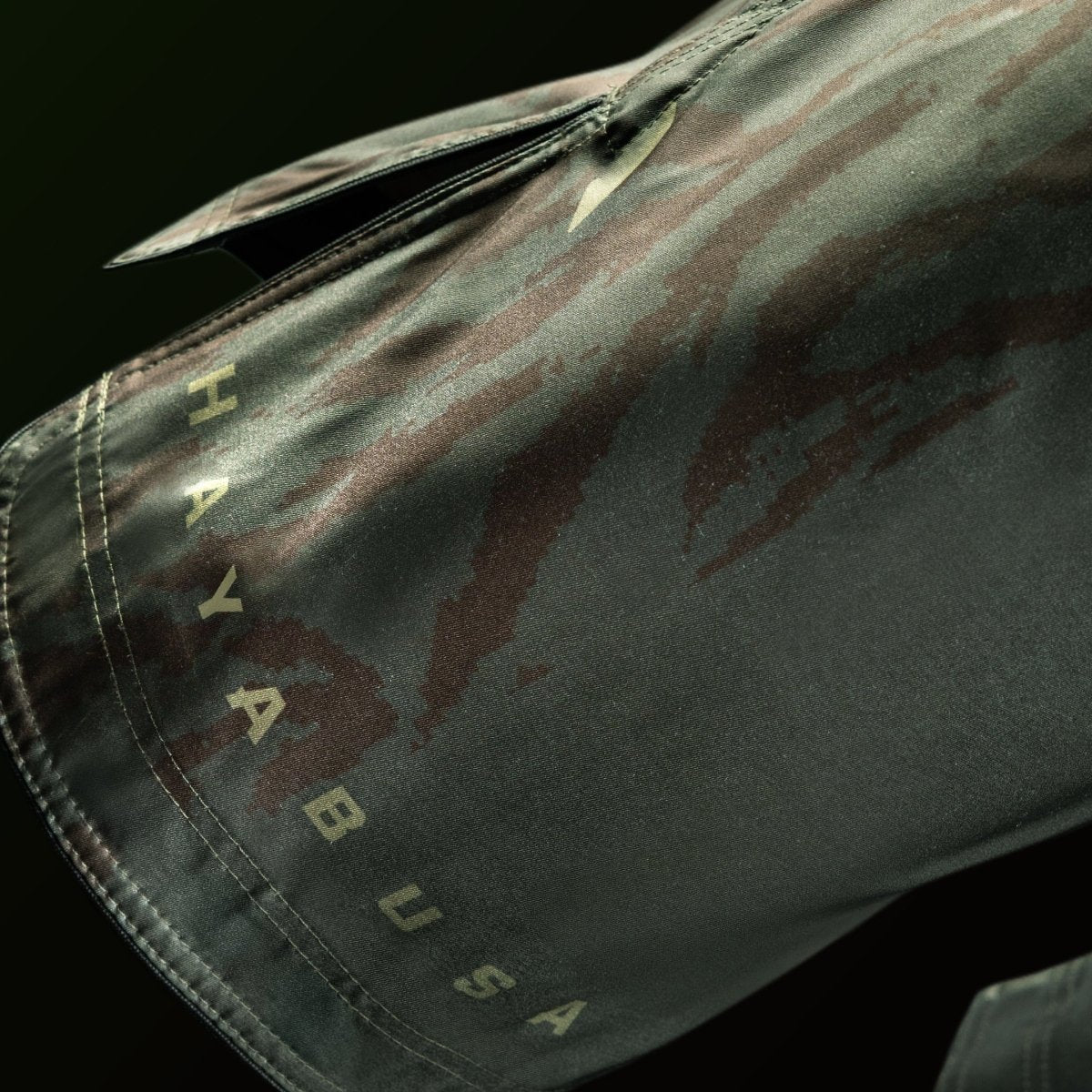 Detalle del logo de Hayabusa y escritura impresa en la pierna de los pantalones cortos verdes de largo completo.