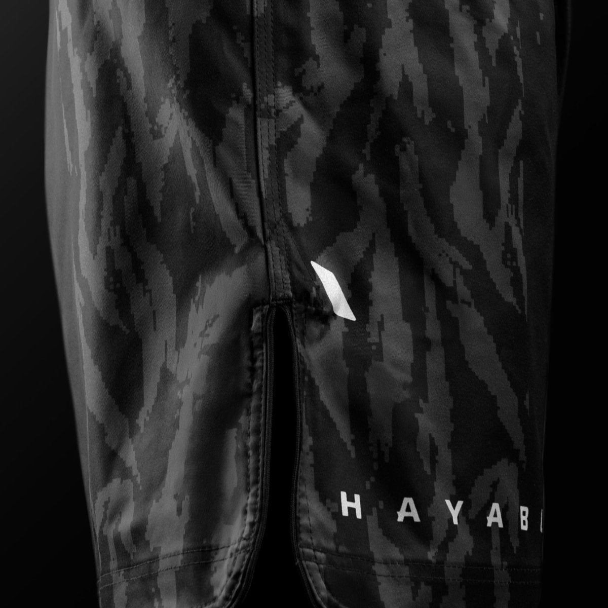 Vista lateral de los pantalones cortos negros de MMA Hayabusa Apex Mid-Thigh MMA con detalle de ventilación para máxima movilidad