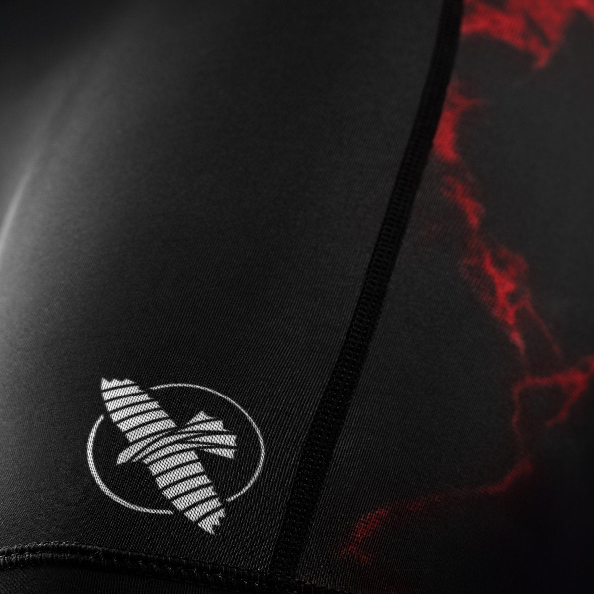 Detalle del logo oficial de UFC en la pernera del pantalón corto negro y rojo de mujer Vale Tudo