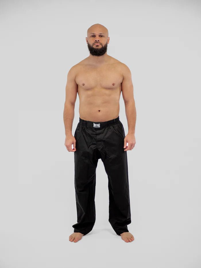 Vista frontal principal pantalones de boxeo de metal Krav Maga negros pose de técnica de defensa personal desgastada