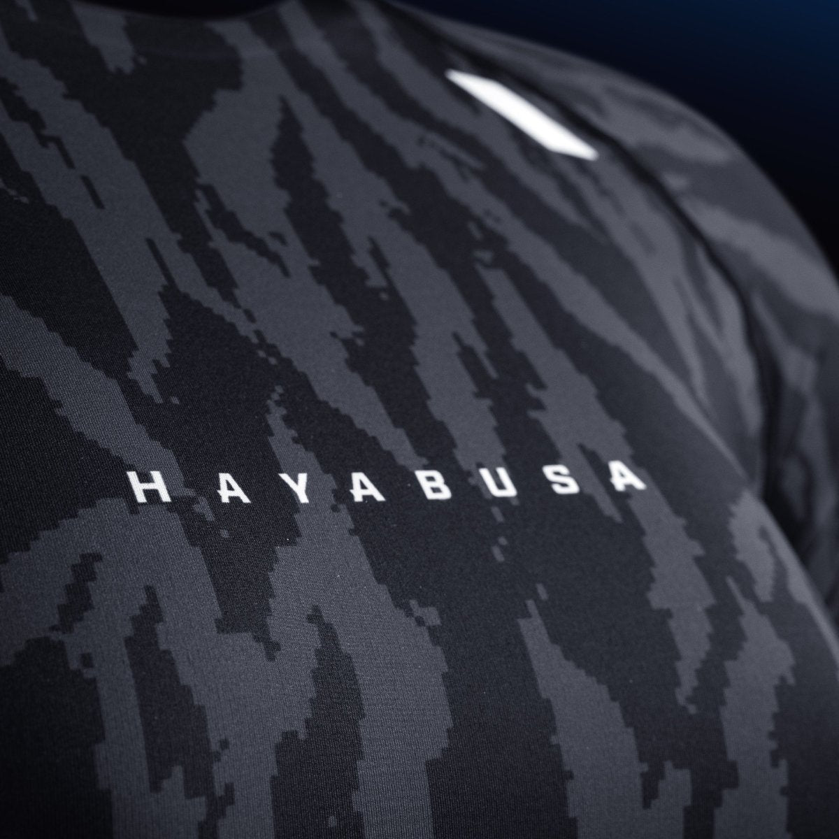 Detalle de la escritura y el logo de Hayabusa en el pecho de la lycra negra, estampado resistente al desgaste