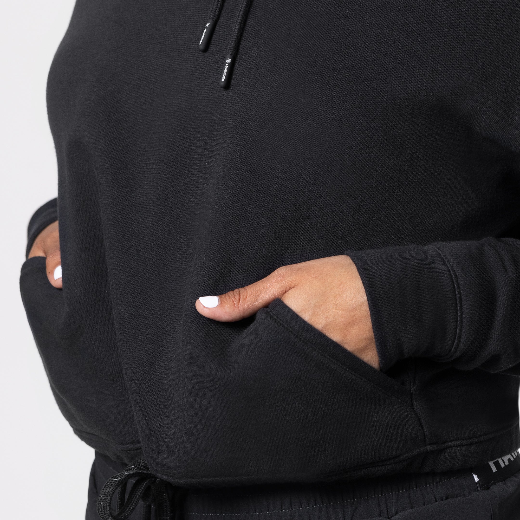 Dettaglio delle tasche anteriori aperte sulla felpa cropped Hayabusa nera