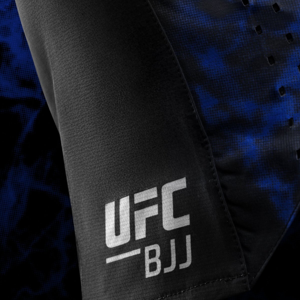 Boční detail oficiálního loga UFC BJJ vytištěný na černomodrých dámských šortkách