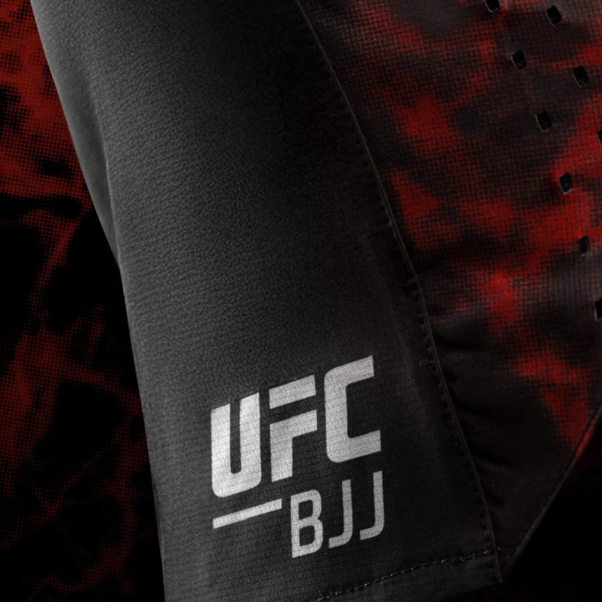 Detail bočního loga UFC BJJ na černých a červených dámských šortkách