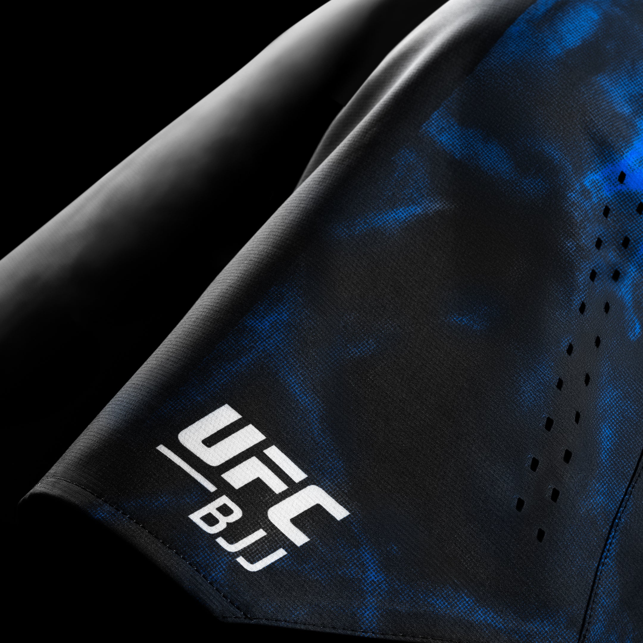 Dettaglio del logo e della grafica UFC BJJ sui pantaloncini da competizione neri e blu