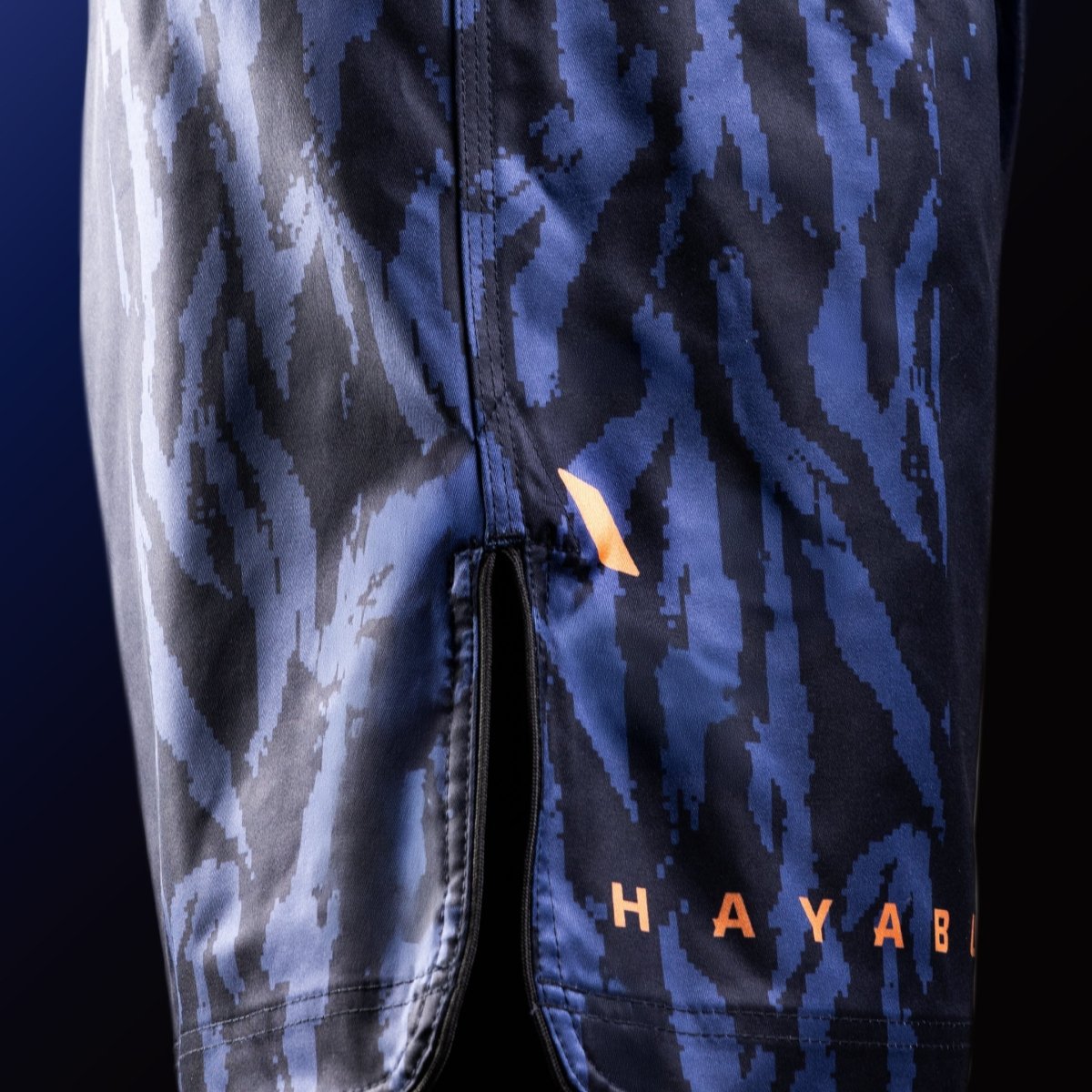 Vista lateral de los pantalones cortos azules de MMA Hayabusa Apex a mitad del muslo con detalle de ventilación para máxima movilidad