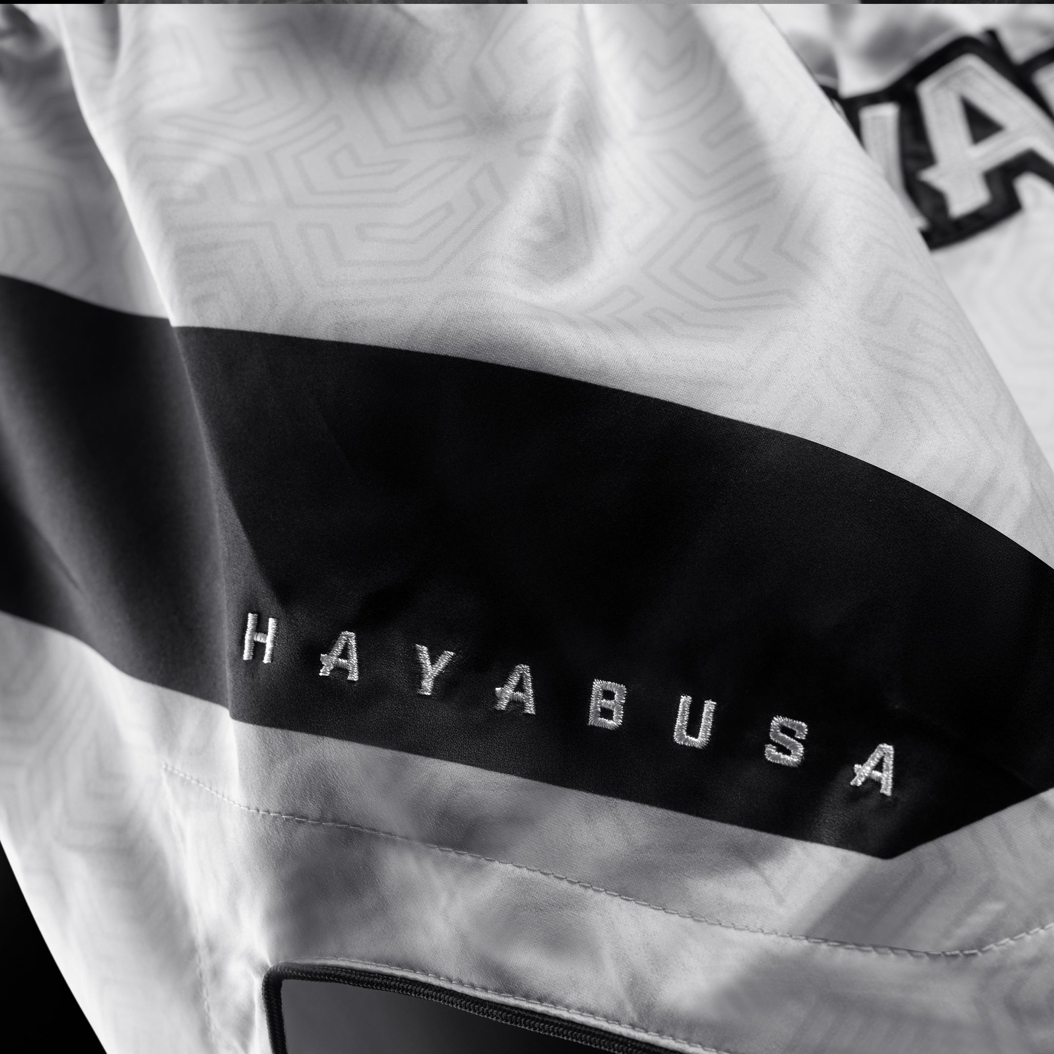 Dettaglio del tessuto tecnico e del logo sui pantaloncini Hayabusa Core bianchi