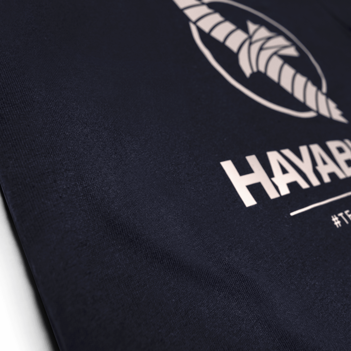 Primer plano del gráfico de silicona del equipo Hayabusa en la camiseta azul medianoche.