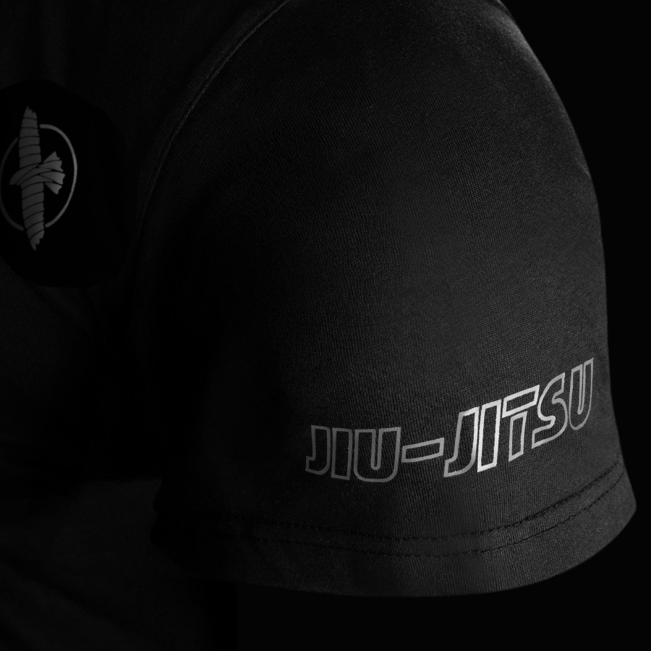 Dettaglio ravvicinato della manica della t-shirt Hayabusa UFC BJJ nera, mostra la cucitura rinforzata e il logo falcon ricamato